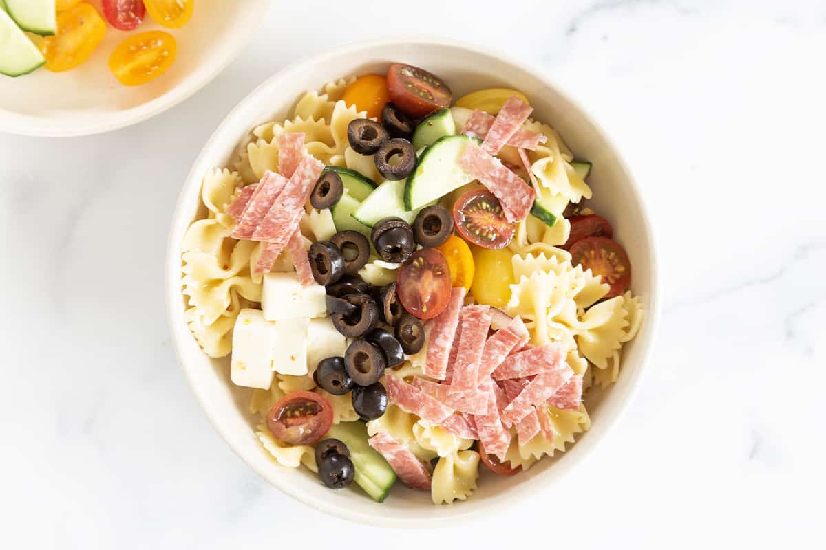 Pasta salad in white bowl with toppings. 