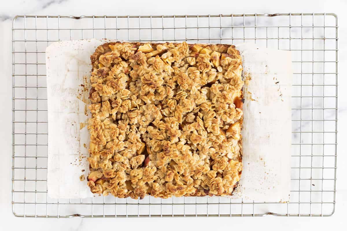 Peach crumb bars on cutting board and cooling rack.