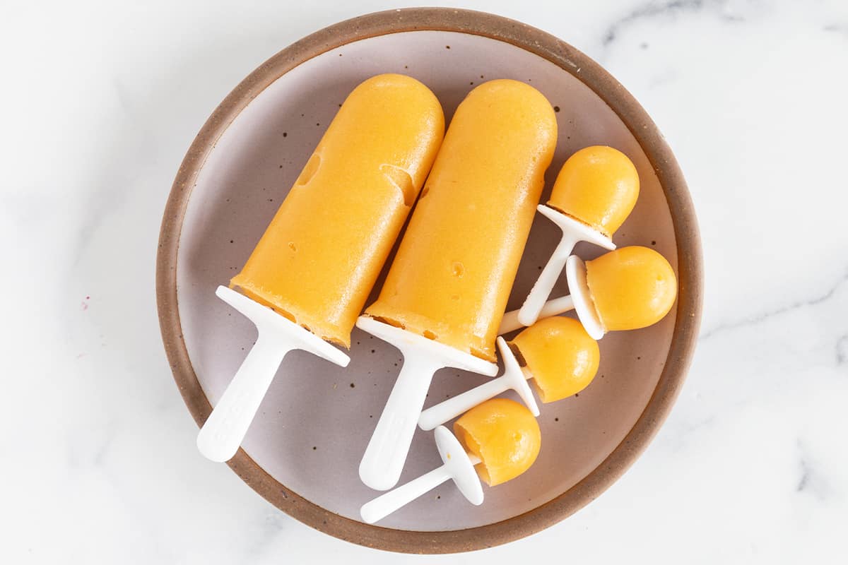 Peach popsicles on grey plate.