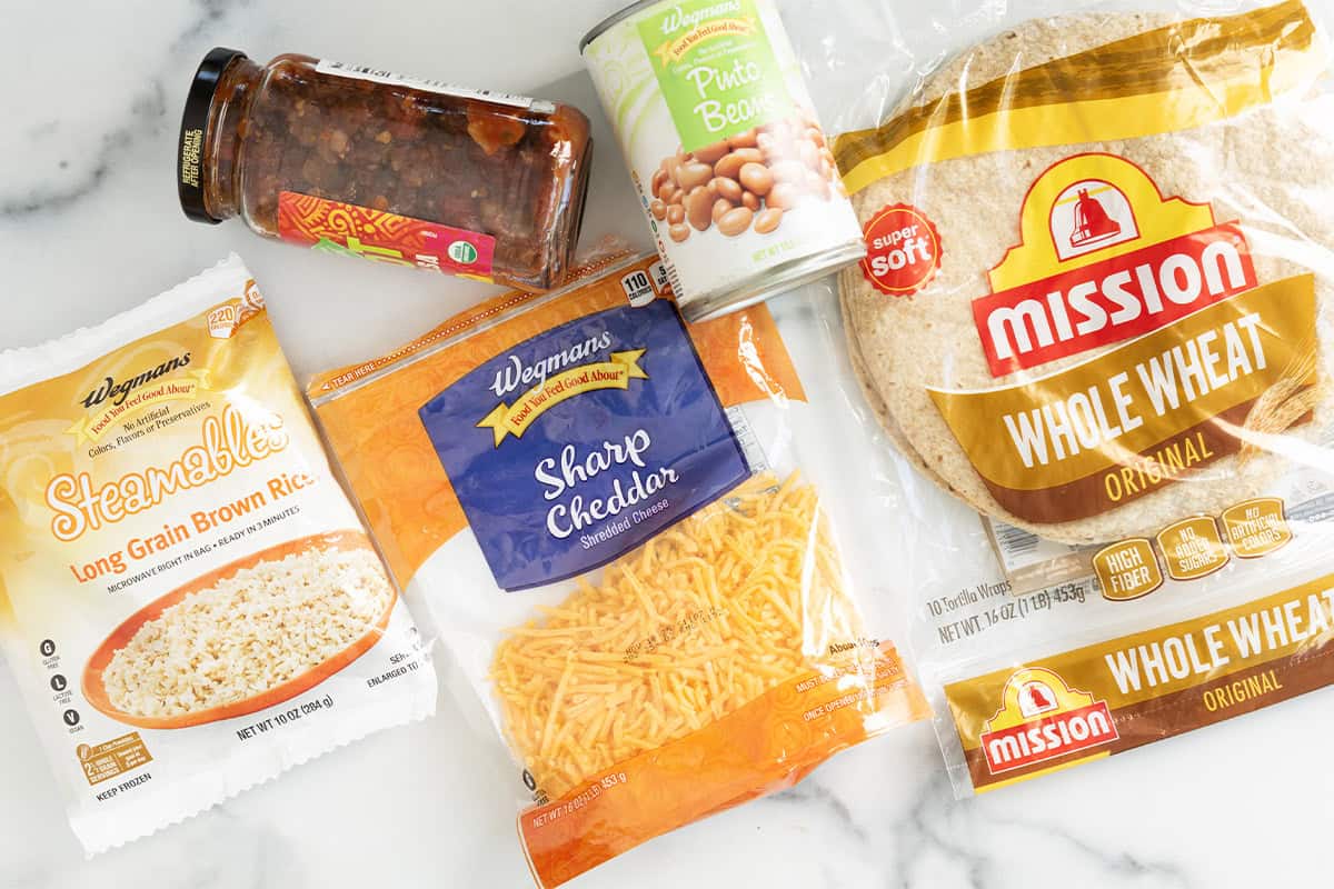 Ingredients for rice and bean burritos on countertop.