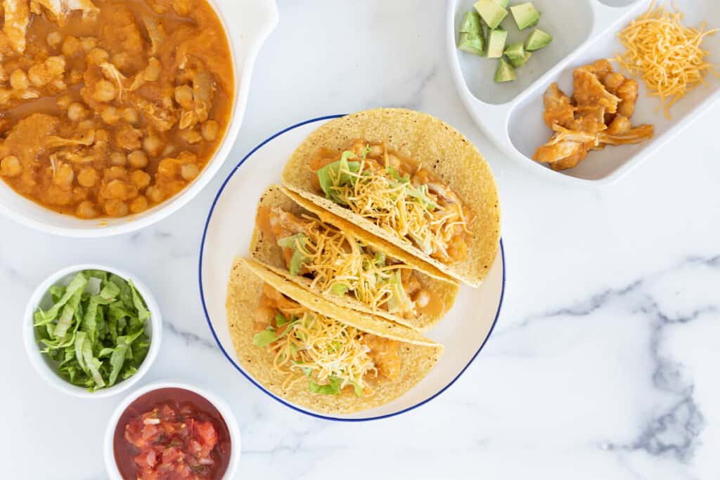 Slow cooker chicken tacos on plate with sides.