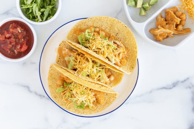Slow cooker chicken tacos on plate with sides.