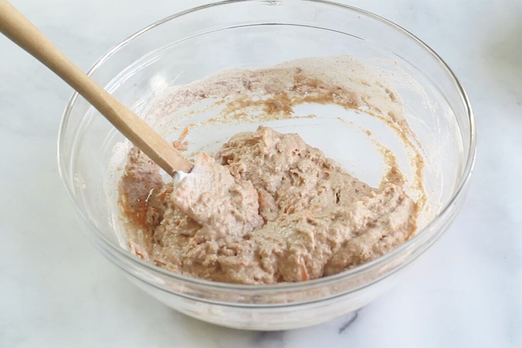 batter for carrot pancakes in glass bowl with spatula.