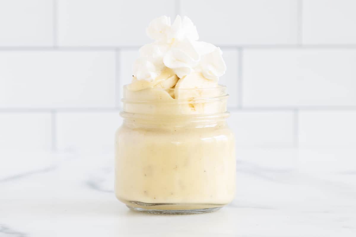 Banana pudding in glass jar with whipped cream.