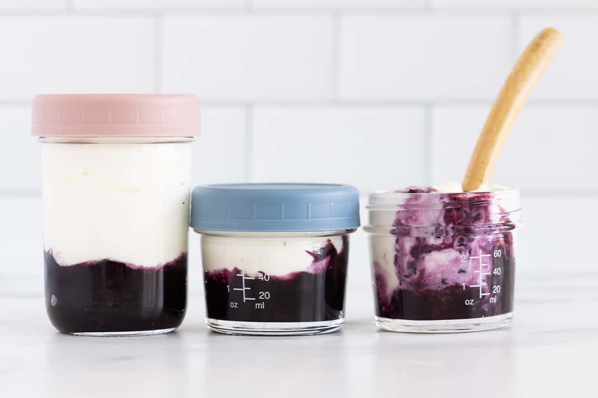 Blueberry sauce on top of yogurt in three jars. 