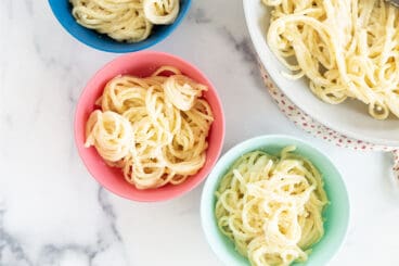 cauliflower alfredo sauce with pasta in colorful bowls.