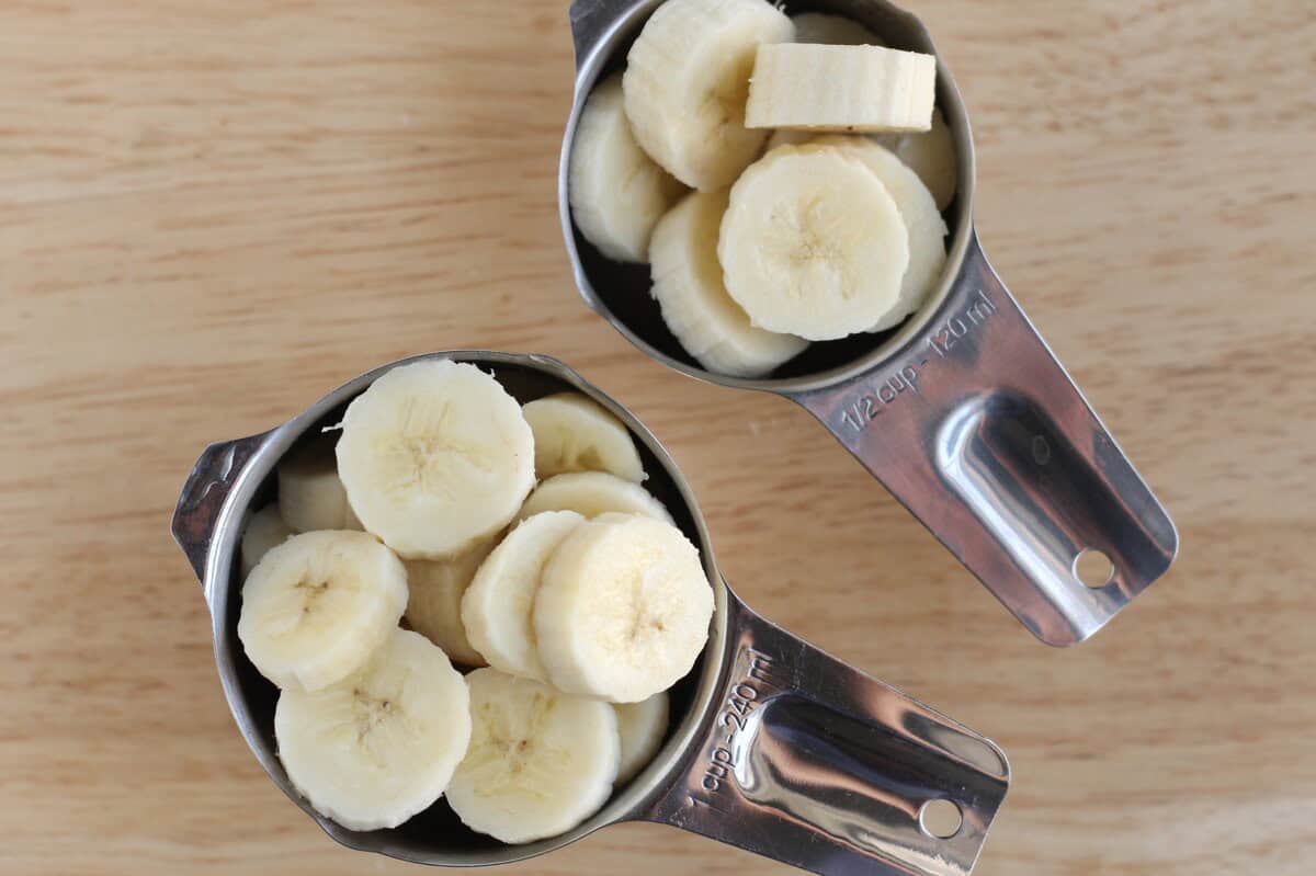 Banana slices in measuring cups for banana cupcakes.