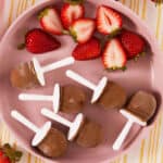 fudge pops with strawberries on pink plate.