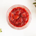 strawberry sauce in jar with berries on counter.