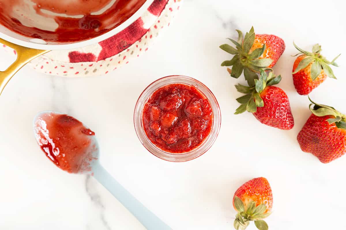 strawberry sauce in jar with spoon on counter.