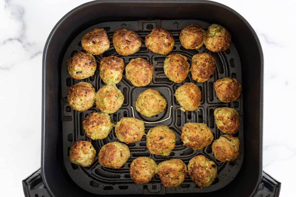 cooked pesto meatballs on air fryer tray.