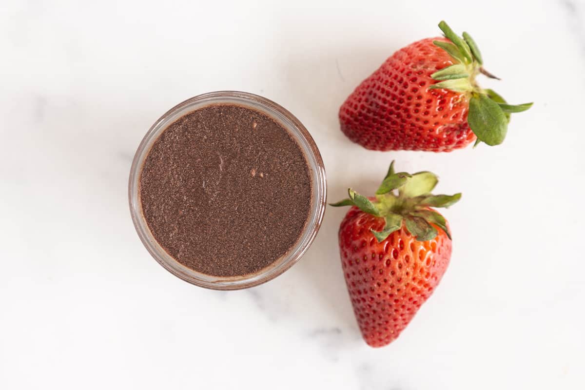 Chocolate mousse in glass jar with strawberries on side.