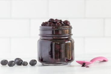 blueberry sauce in jar with pink spoon.