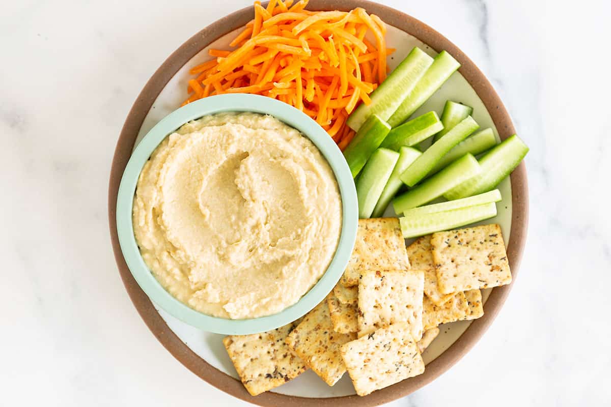 hummus without tahini with dippers on plate.