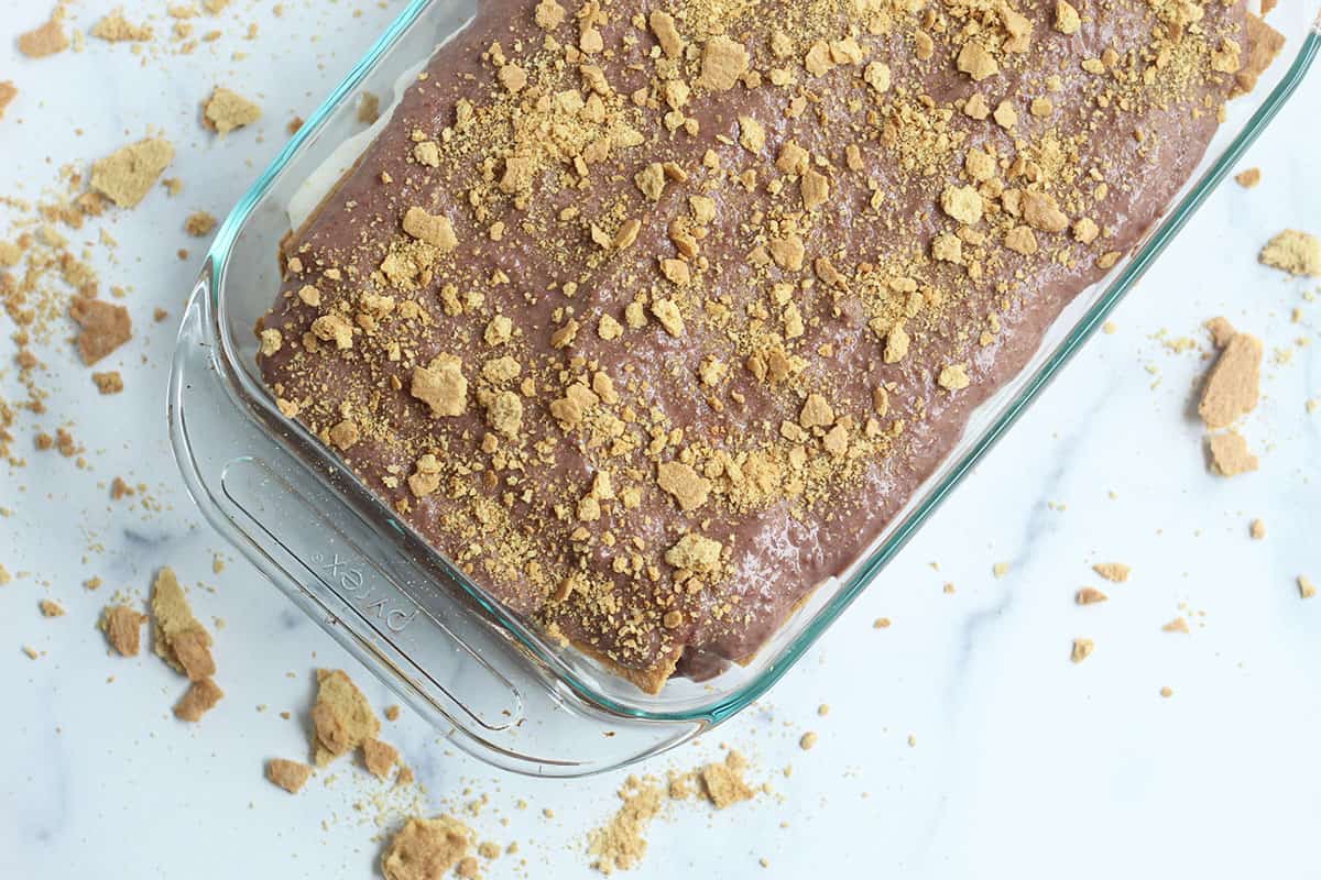 adding crushed graham crackers to top of ice box cake.