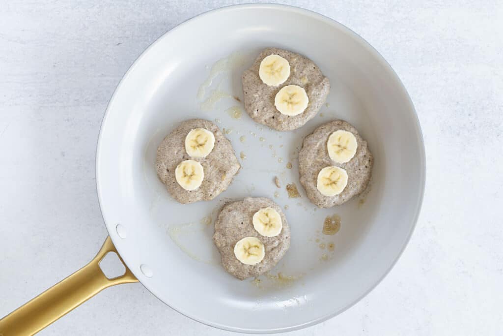 cooking vegan banana pancakes in skillet.