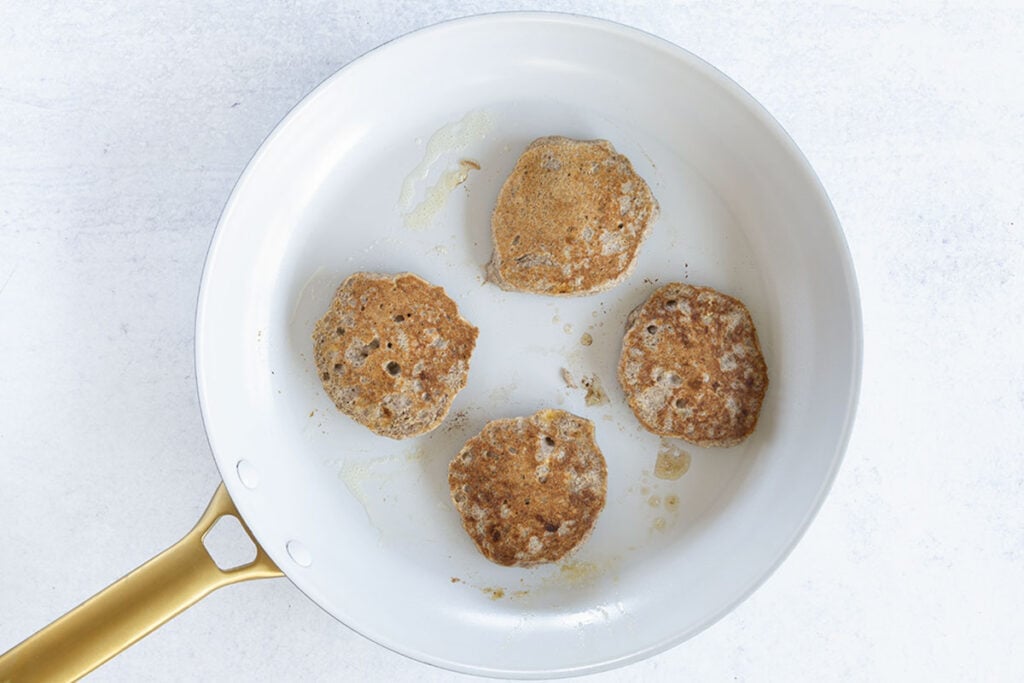 cooked vegan banana pancakes in white skillet.