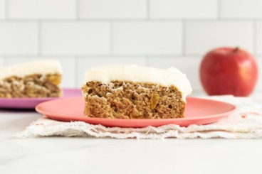 Two slices of applesauce cake on plates with apple in background.