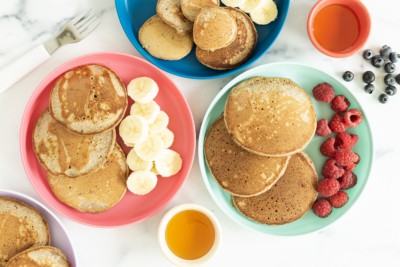 buckwheat pancakes on three plates with sides.