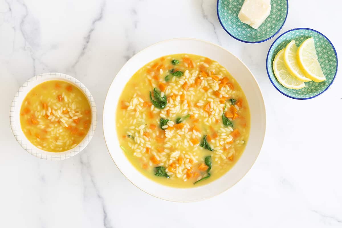 Orzo soup in bowl with sides.