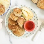 Applesauce pancakes on plate with syrup and apples.