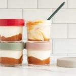 Peach yogurt in glass jars stacked on counter with spoon.