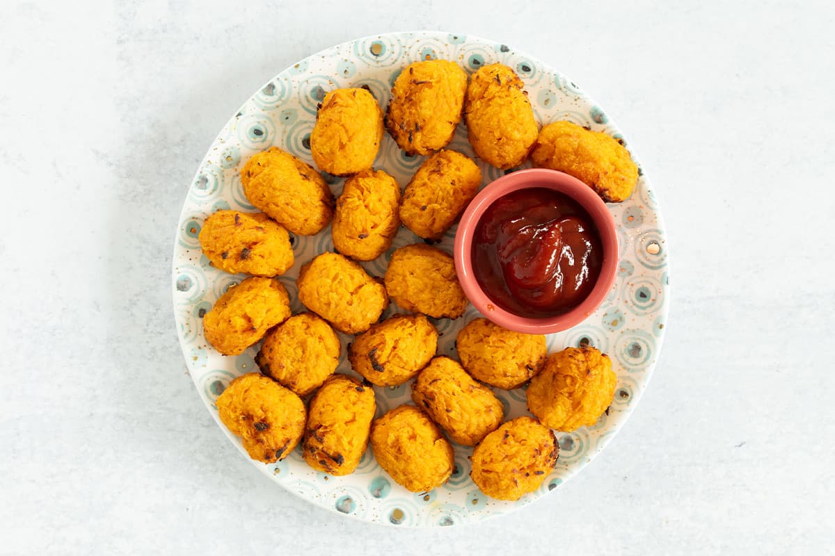 Sweet potato tots piled on plate with sides.