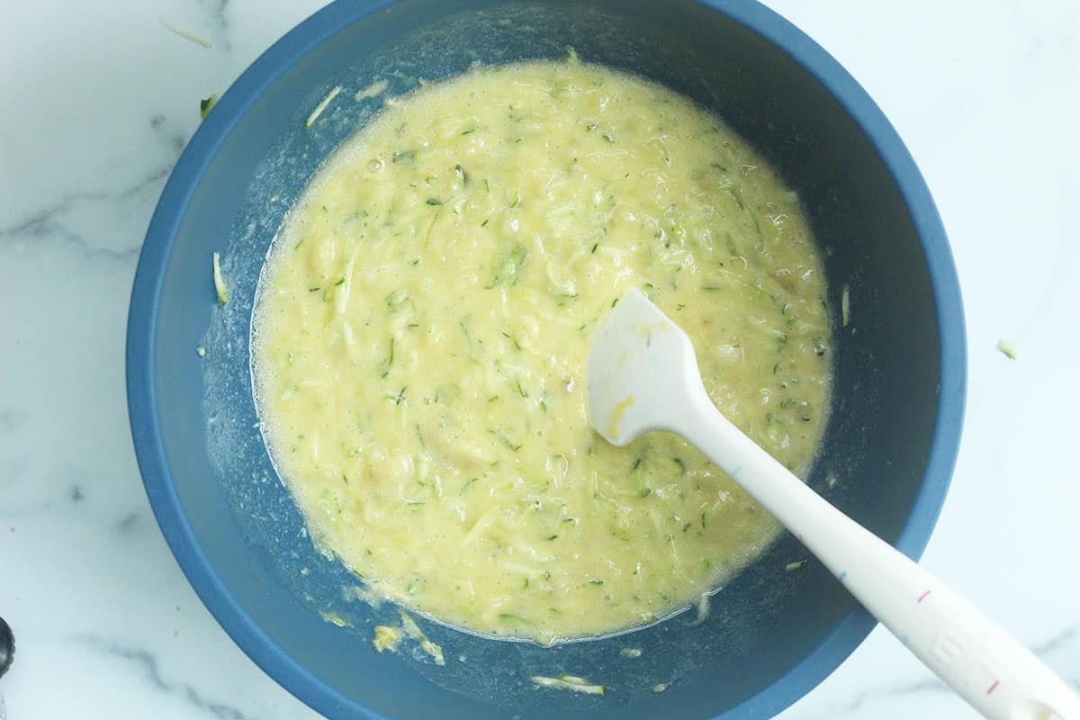 Wet ingredients for zucchini banana bread in blue bowl.