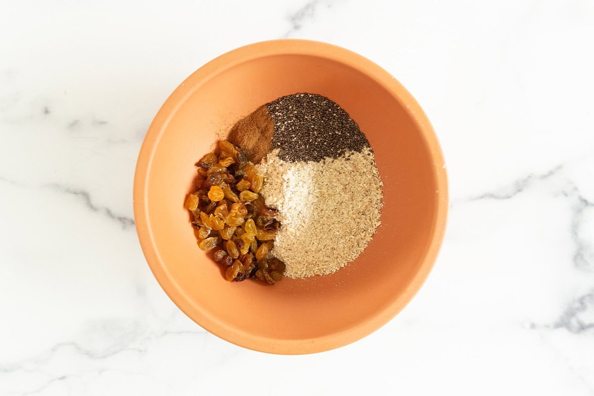 Ingredients for oatmeal cups in orange bowl before mixing.