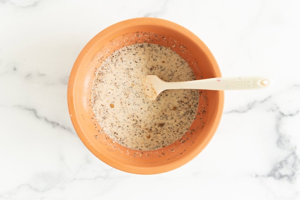 Mixture for oatmeal cups in orange bowl with spoon.