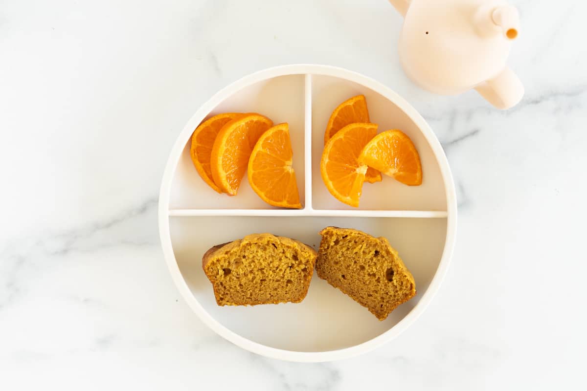 Pumpkin muffin on kids plate with oranges.