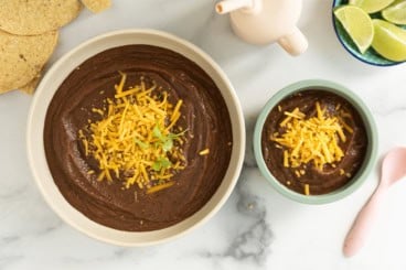 Black bean soup in two bowls with toppings.