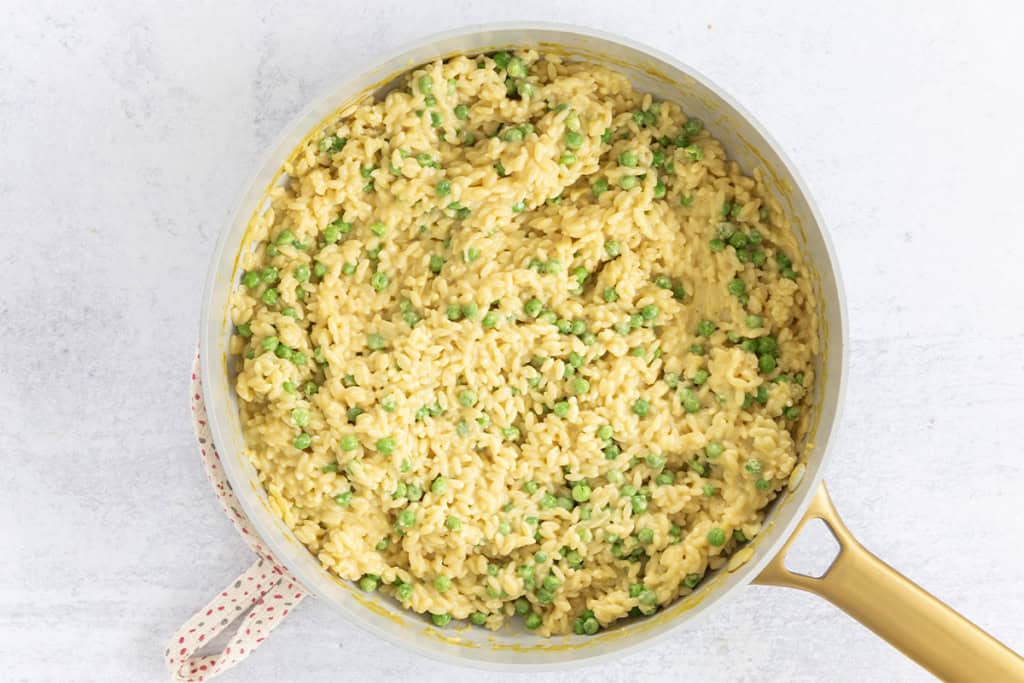 Orzotto with peas in pan.