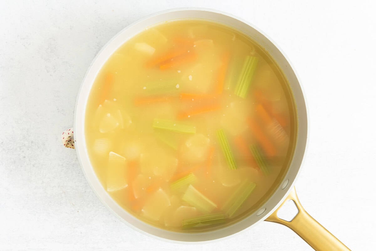 Veggies cooking in water for pasta in broth.