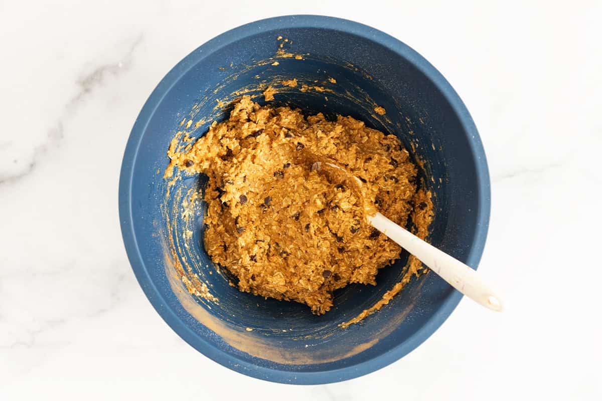Batter for pumpkin oatmeal cookies in blue bowl with spoon.