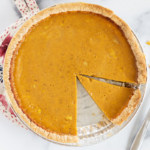 Pumpkin pie in pie tin with pieces cut out.