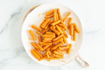 Roasted baby carrots on white plate.