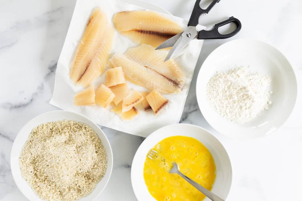 Cutting fish into nuggets and breading them for fish nuggets.