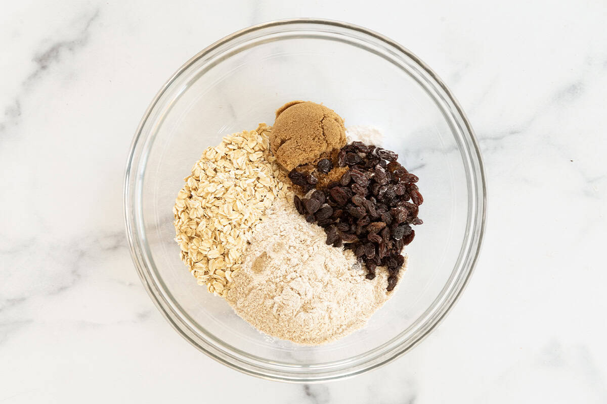 Ingredients for oatmeal raisin cookies in glass bowl before mixing. 
