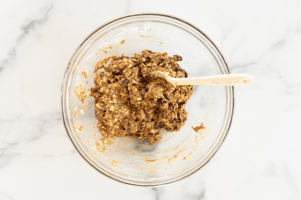 Batter for oatmeal raisin cookies in glass bowl.