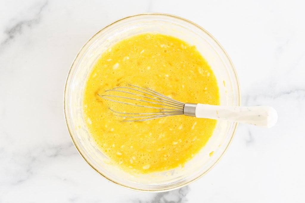 Egg mixture in glass bowl for sausage egg muffins.