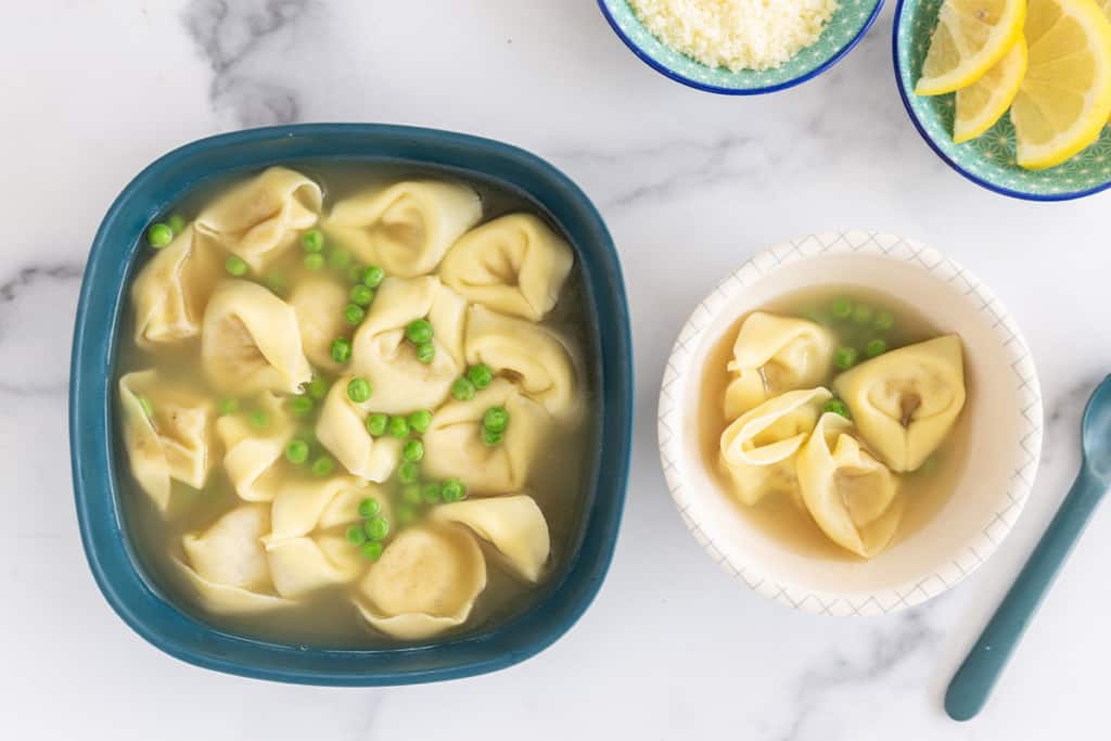 Tortellini in broth in two bowls with sides.