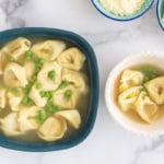 Tortellini in broth in two bowls with sides.