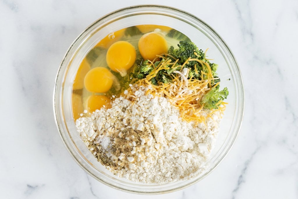 Ingredients for broccoli egg bake in glass bowl before mixing.
