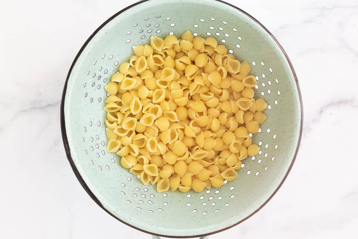 Noodles in strainer for hidden veggie mac and cheese.