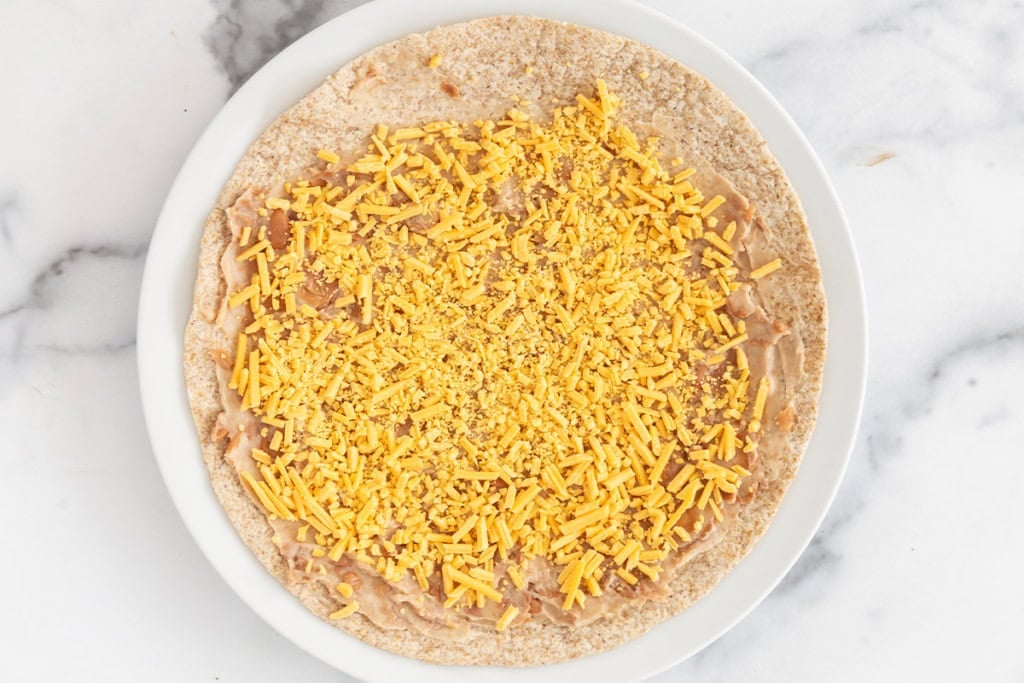 Tortilla with beans and cheese for taco roll ups.