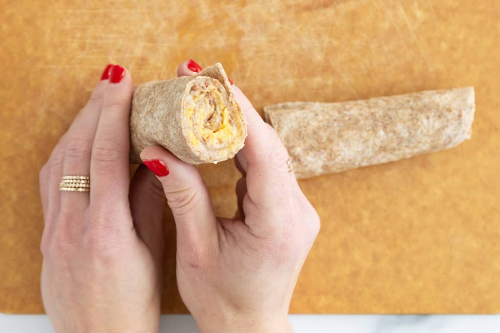 Taco roll ups being made on cutting board.