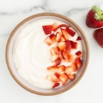 Vanilla yogurt in bowl with strawberries.