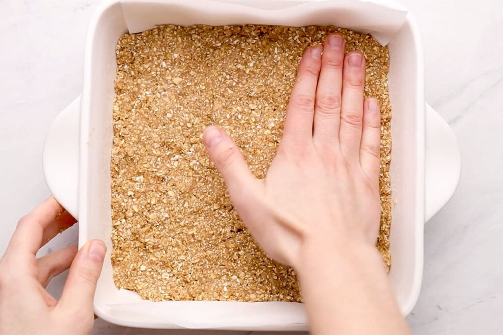 pressing batter for breakfast bars into pan with hand.