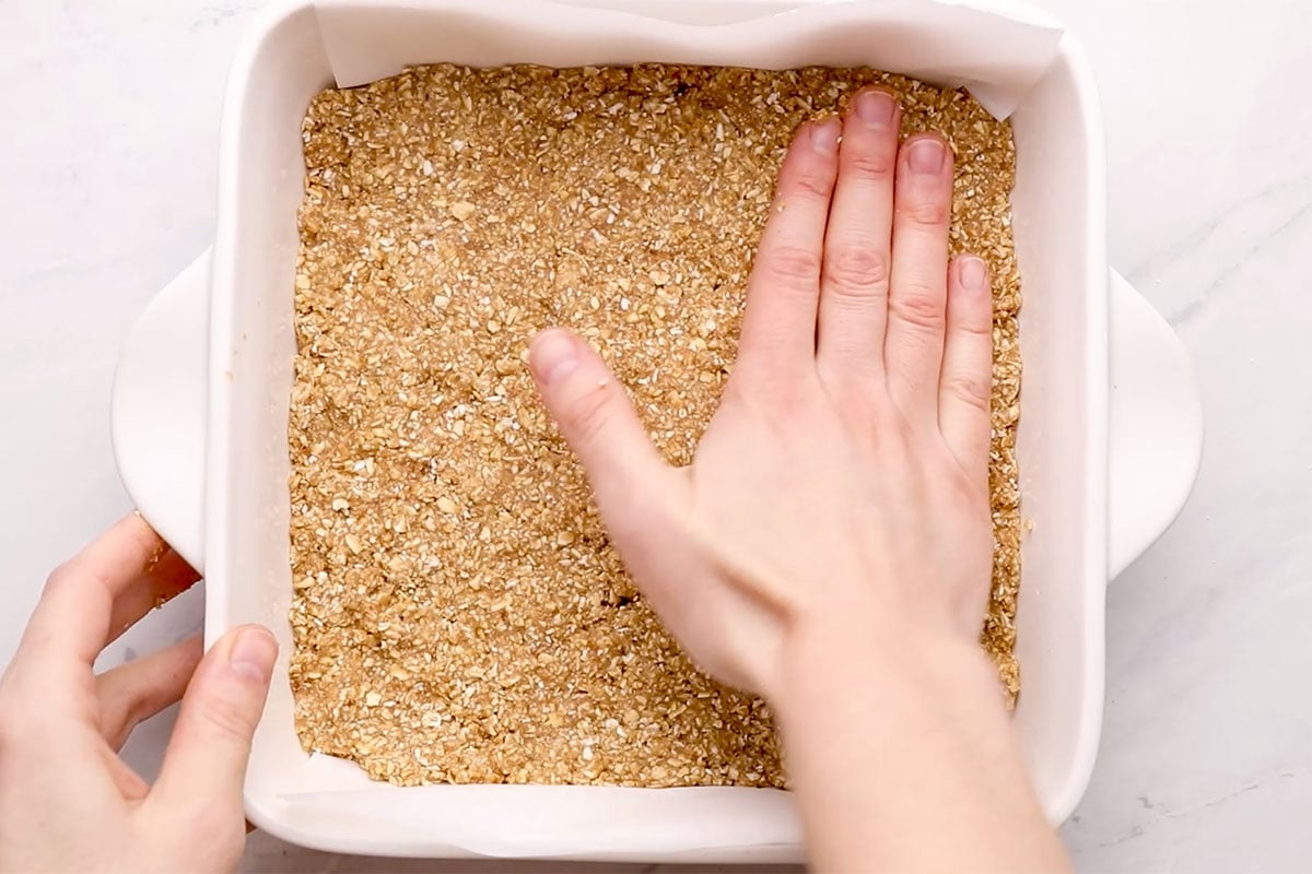 pressing batter for breakfast bars into pan with hand.